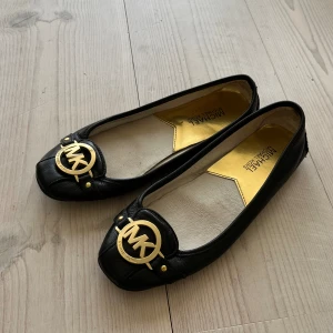Svarta ballerinaskor  - Svarta ballerinaskor från Michael Kors i fint skick, endast lite slitna på insidan (kom privat för fler bilder). 23,9 cm inuti vilket motsvarar storlek 37. Står storlek M7 på insidan. Använd gärna köp nu!