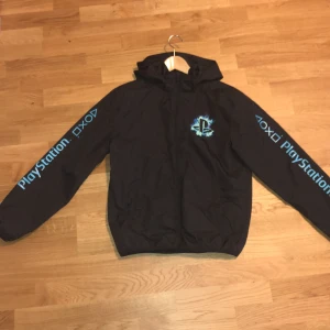 Playstation windbraker för barn - Vår och höst jacka. Den har storleken 158/164 och passar bra till dem som är i åldrarna 12-14. Jackan har färgerna blå, vitt och svart. Jackan är i god skick. Ordinarie pris: 400kr