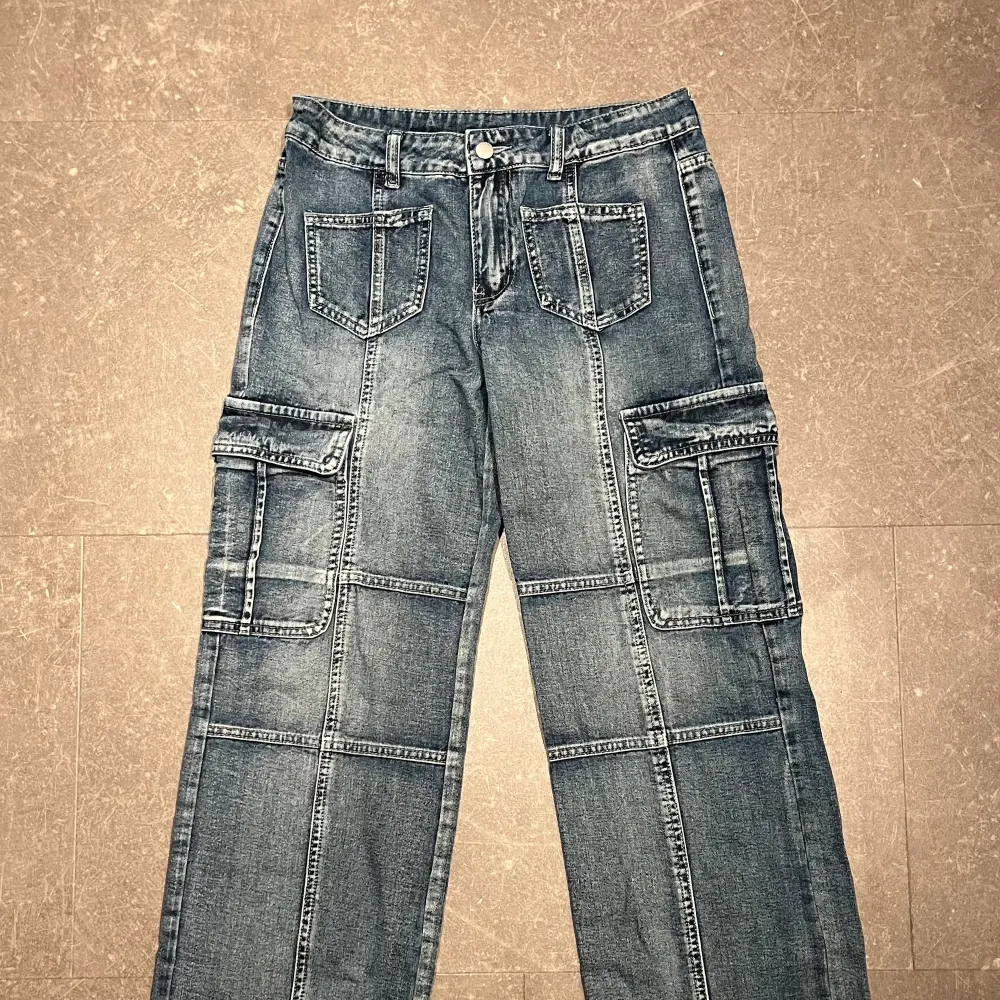 Lite mörkblåare cargo-jeans i storlek 36. Modellen är straight och de är mid-waist, samt med lite fickor och sömmar som detaljer.  Sparsamt använda och säljer då de är lite små och aldrig används.. Jeans & Byxor.