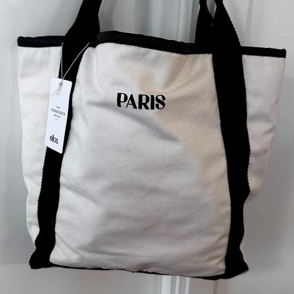 Säljer en väldigt fin ny tygväska med texten: PARIS. Storlek: 30 cm x 30 cm Aldrig använd. Köpt från ELLOS. Perfekt till sommaren / våren och till stranden. . Väskor.