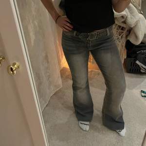 Lågmidjade vintage jeans med utsvängda ben och bälte. Glittriga detaljer längstner på jeansen och bakfickor i en lite mörkare kontrast färg.   Mått:  Midja: 40 cm  Ytterbenslängd: 102 cm  Innerbenslängd: 78 cm  Gren: 23 cm 