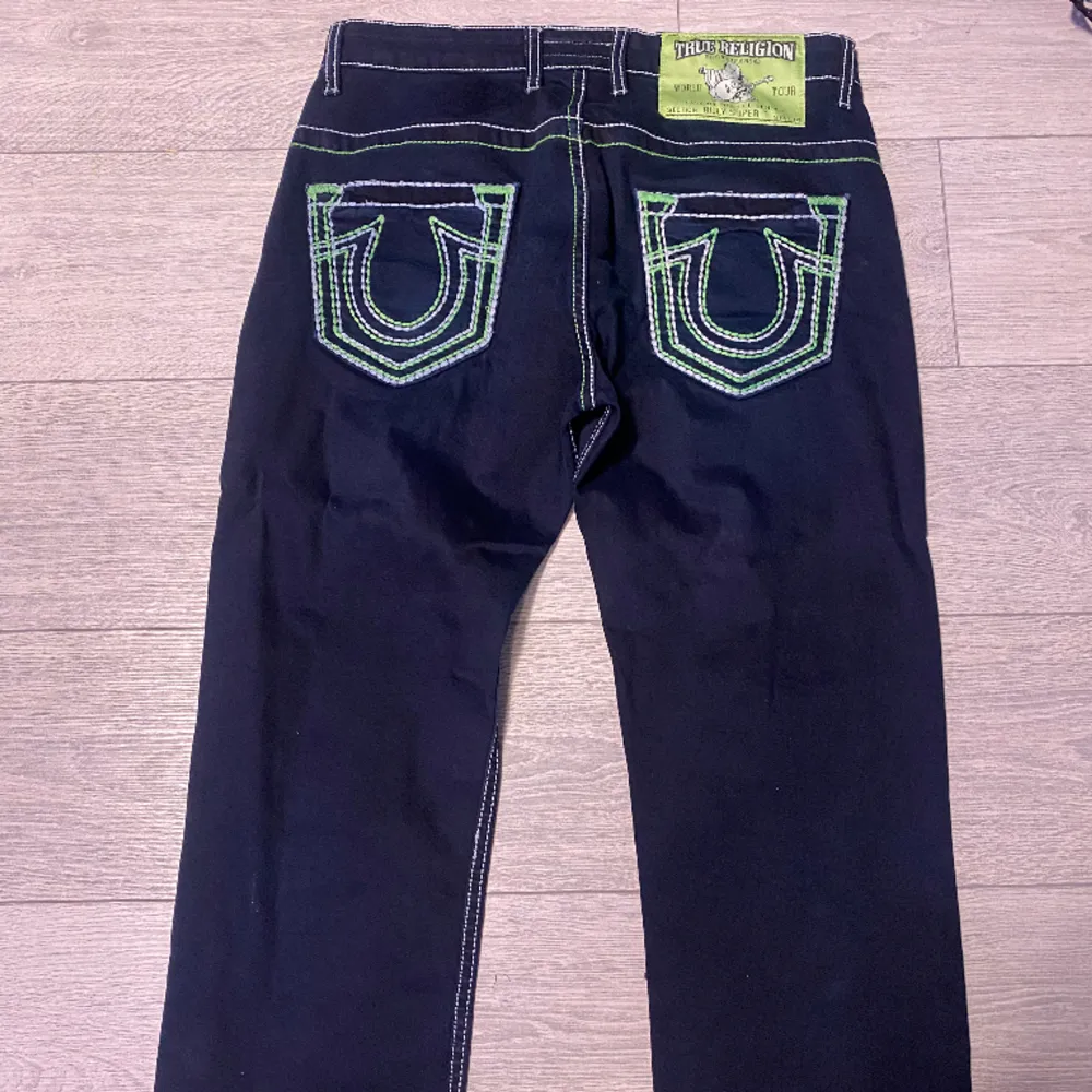 (INTE ÄKTA) säljer ett par mörkblåa med neongrön tjock stygn true religion baggy byxor. Nypris vet ej. . Jeans & Byxor.