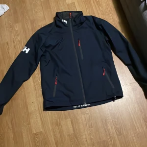 Vindjacka  - En jätte fin och lite använd helly Hansen jacka! Ett litet hål efter att ha fastnat men hållet är väldigt litet. Själva jackan är i väldigt bra skick och använd Max 10 ggr Nypris 2399 kr 