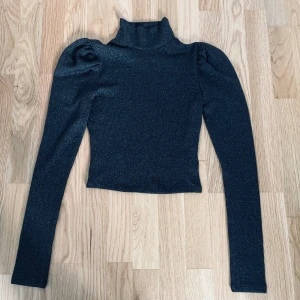 Glittertröja - Tröjan har inga tecken på användning och är endast använd 2 gånger. Den är svart med silver glitter i sig och den har 93 % polyester, 5% metalliserade fiber och sist 2% elastin. Om varan ska skickas betalar köparen för frakten!  