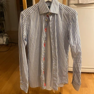 Randig Eton skjorta med blommiga detaljer - Eton skjorta i fantastiskt skick, inga defekter. Slim fit. Storlek kan avläsas på sista bilden.  Ärmlängd: 66 cm Längd (rygg): 76 cm Axel-axel: 43 cm Midja: 91 cm