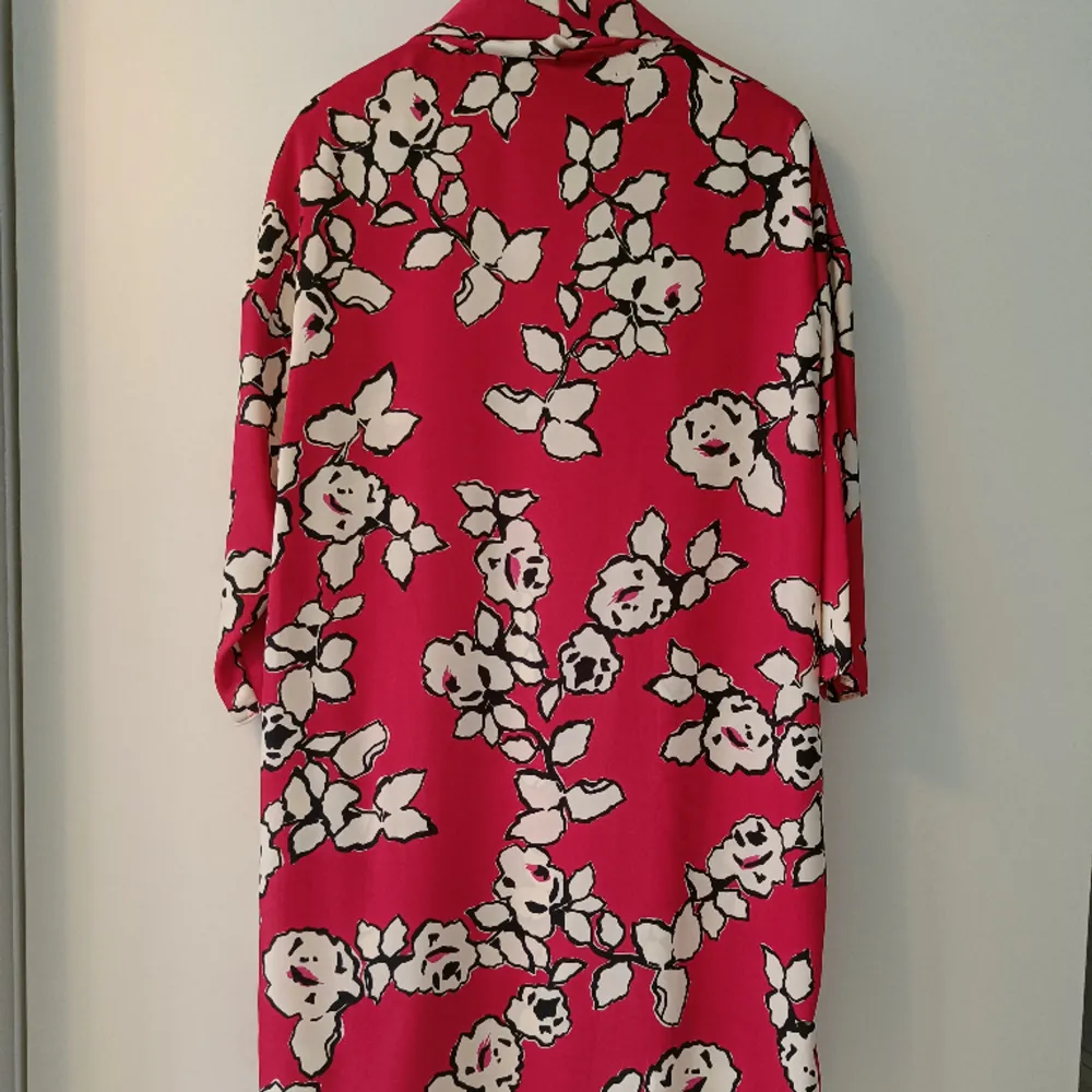 Cerisefärgad klänning med blommönster och tillhörande bälte. Aldrig använd . Klänningar.