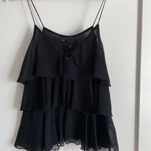 Linne - Säljer nu mitt svarta linne med volanger från Zara i storlek xs, nyskick då lappen fortfarande finns kvar. Skriv om ni har några frågor!