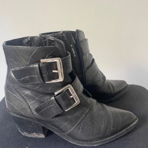 Svarta boots - Ett par snygga svarta boots med spetsig tå och metallspännen. Lite slitna i klacken då jag använt dessa en del, men utöver det är de väldigt fina och hela!☺️