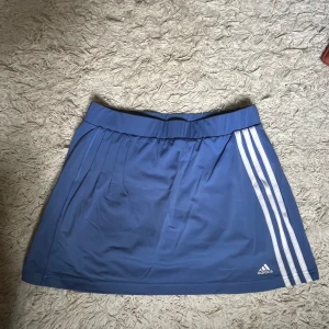 Blå minikjol / tenniskjol från Adidas - Har inbyggda shorts. Passar perfekt på mig som har strl S. De är väldigt stretchiga i materialet så passar nog xs-m
