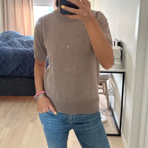 Kortärmad T-Shirt - Beige stickad tröja med korta ärmar från St. Tropez. 