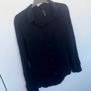 Skjorta svart  - Tunn skön skjorta i ett jätteskönt flowy material(obs ej struken på bilden 🙈). Helsvart med svarta knappar i storlek L