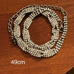 Silvrigt halsband med vita stenar - Ej silver. Missfärgningar förekommer, mest på baksidan.