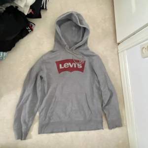 Grå hoodie från Levis, använd men i bra skick. Muddarna är lite slitna men inget som märks, storlek S