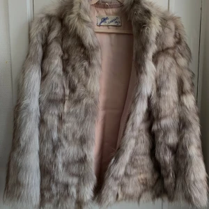 Vintage pälsjacka  - Vacker pälsjacka med glansigt ljusrosa foder. Pälsen är ljusgrå med inslag av vitt och brunt. Från Garanti päls AB. 50-60-tal   MÅTT: tot längd: ca 70 cm  armhåla-armhåla: ca 56 cm  ärm mätt från armhåla: ca 40 cm   Uppskattar storleken till M