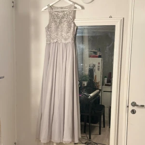 Balklänning - En ljusgrå balklänning med kristaller💕 Storlek 34 och proffesionellt uppsydd hos skräddare, så passar om man är 160-165 cm. Köpt på About You och märket Laona. Använd endast en gång. Nypris 2269 kr.