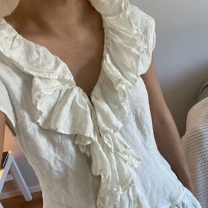 Volang blus i linne - Så söt vit blus i linnetyg med volanger! Perfekt till sommaren💗😊Toppen skick! Storlek 44 men sitter löst på mig som har 34/xs. Hör av dig vid frågor🫶🏼