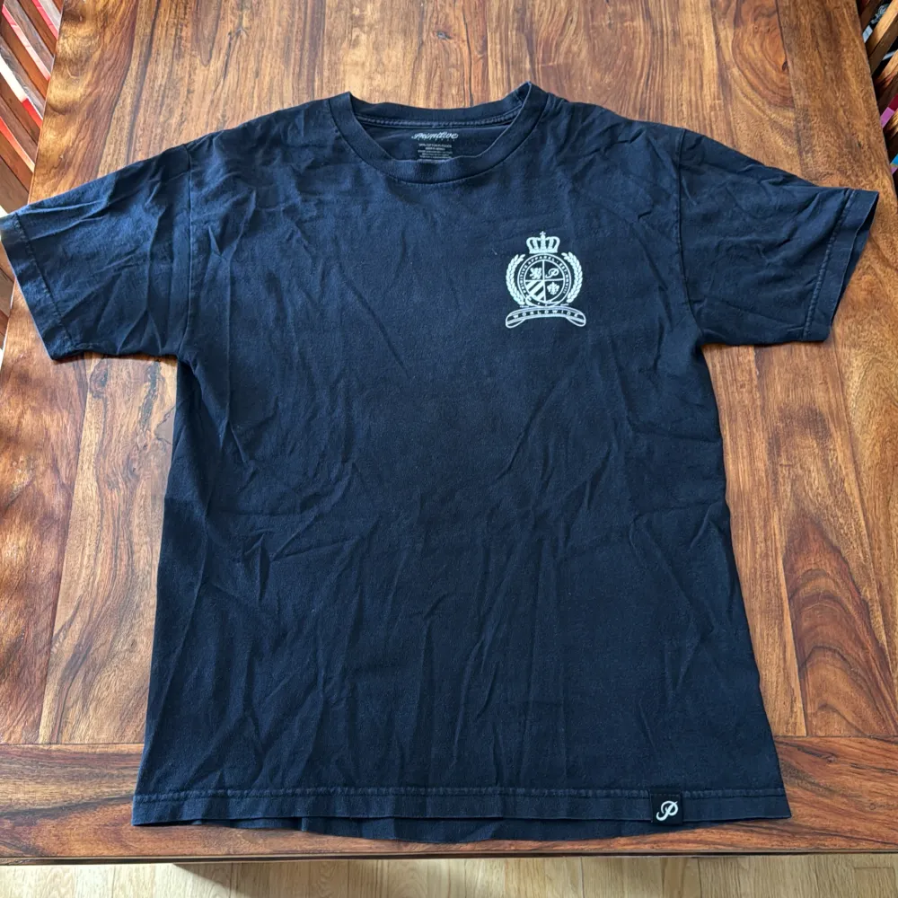 En svart primitive T-shirt med tryck på framsidan och baksidan. En hyfsat använd tröja med mycket kvar att ge. Condition: 6/10. T-paidat.