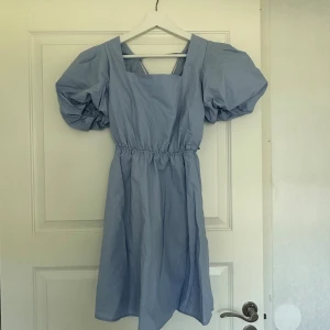 Blå klänning med puffärm och snörning i ryggen  - Säljer denna blå klänning med puffärm och snörning i ryggen som är helt ny med prislapp kvar från NA-KD. Se sista 2 bilderna för att se hur modellen ser ut på. Strl 36 och säljer för 150kr 