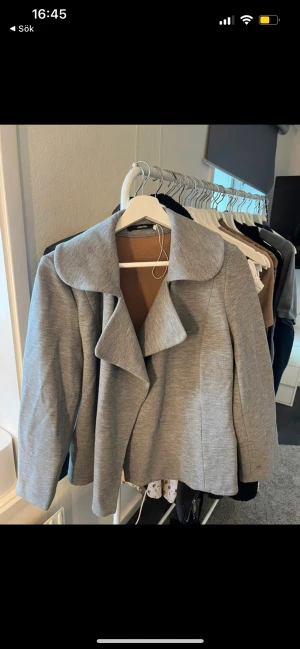 Tunn kappa - Tunn grå kappa. Den har en liten fläck på ena ärmen (se bild). Annars är den i bra skick