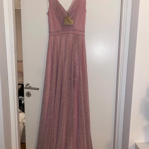 Balklänning (aldrig använd) - Storlek UK 8  Ljus rosa glittrig klänning. Skriv mer för mer information 