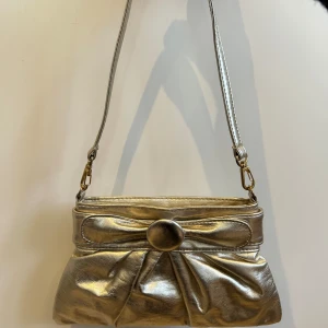 Silvrig väska - Supersöt silvrig (skimrar i guld också) väska! Perfekt till fest! Från märket Pieces. Inga synliga defekter. Pris kan diskuteras.