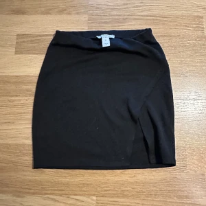 Svart minikjol - Svart bomulls minikjol med slits från Nelly, storlek XS