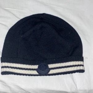 Moncler mössa - Detta är en 100% äkta moncler mössa som inte används. Skick är 10/10, köpte den för 1200kr och säljer den för 800kr men pris kan diskuteras!