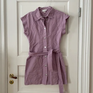 Lila klänning  - Lila klänning från Monki i storlek S. Figursydd och knäpps med knappar. Avtagbart band i midjan. Använd en gång, i fint skick. Bara att fråga om det är något du undrar! Kan mötas på Järntorget i Göteborg eller skicka, köparen står för frakt.