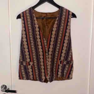 Mönstrad Väst - Mönstrad väst med brun insida och knappar. Bra skick. Har inte koll på märke eller storlek.