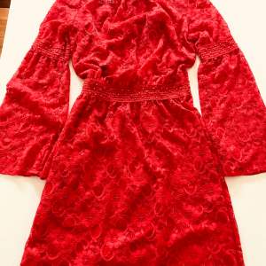 Klarröd spetsklänning med röd underklänning. Pärldetaljer på ärmar och midja