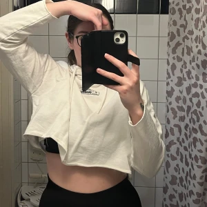 Vit kort hoodie - Vit kort Hoodie med minimalistiskt tryck i fram. Har luva. Väldigt tunt material och passar till träning. Storlek 40 från Boohoo.