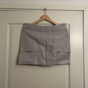 Minikjol - Ljusgrå miniskirt i faux skinn med fina detaljer, ursäkta rynkig på bilden. 