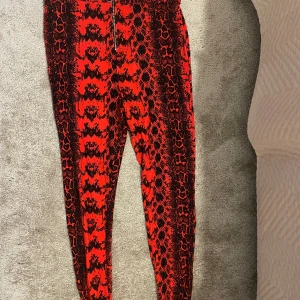 Röd svarta tuffa tygbyxor helt oanvända nyskick  - Svart röda tygbyxor med dragkedja. Helt oanvända 