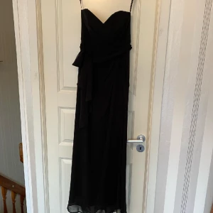 Klänning - Enkel svart festklänning med ett band som går att ta bort alt. Knyta runt midjan eller ryggen.
