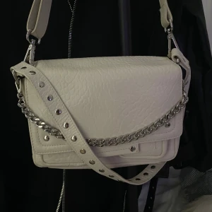 Nunoo - Vit väska från nunoo. Finns så man kan ha den på axeln och även som exelremsväska 