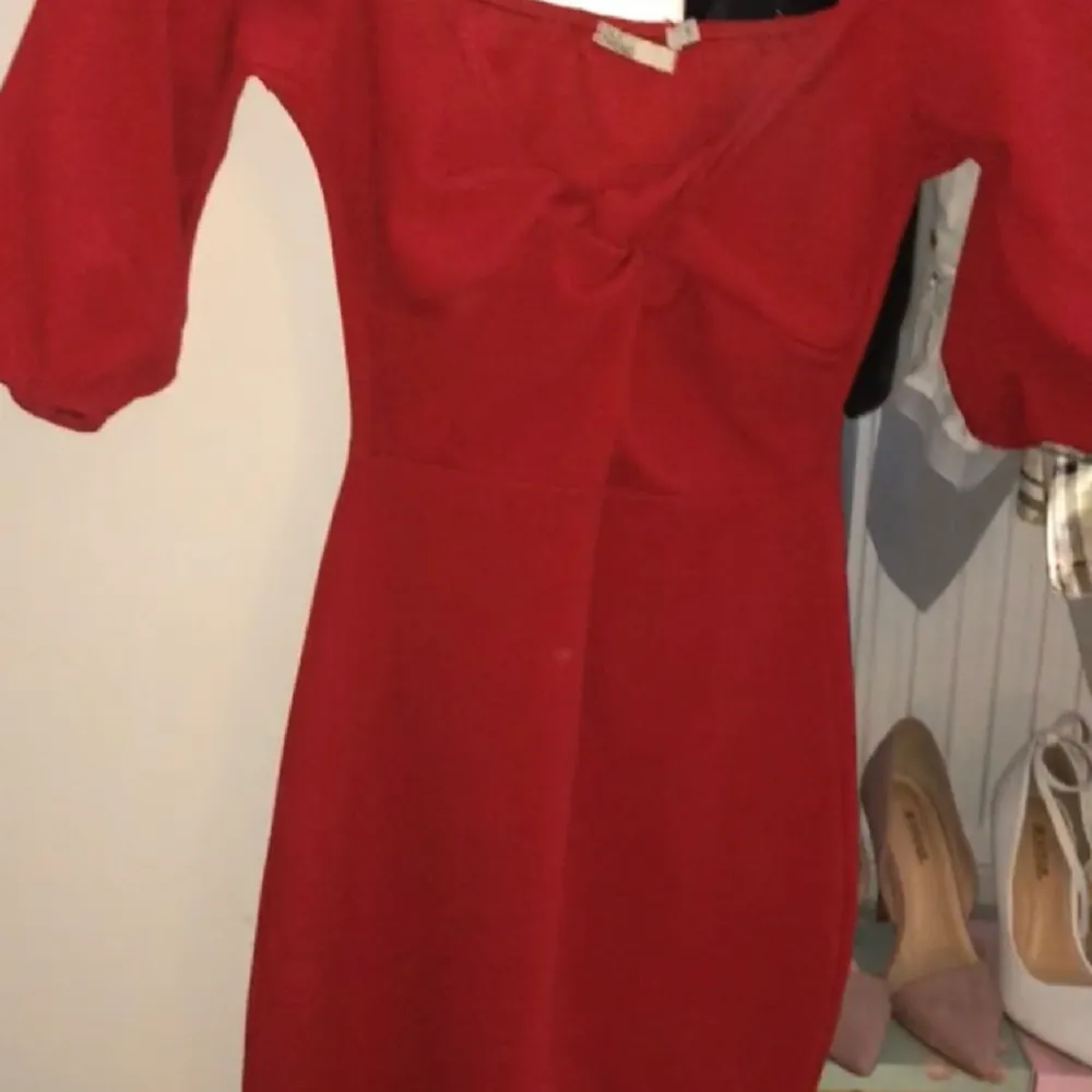 En tight röd klännnin som är lite öppen vid bröstet . Klänningar.