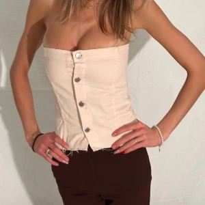 denimtopp - rosa bandeautopp i denim med knappar fram. mycket stretch i toppen pga jeansmaterialet. tjejen på bilden har i vanliga fall xs-s, inte så 