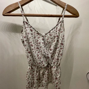 Blommigt linne - Sött linne med rosa blommor, storlek XS, tidigare från BikBok. Banden är sydda bak pga av att de varit för långa. 