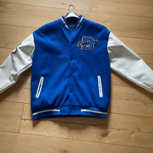 Lätt jacka med tryck och broderi - Blå lätt jacka, kan bäras både inomhus och ute. Jackan har broderat tryck fram, bak och på ena ärmen. 