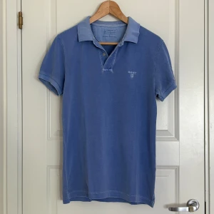 Gant piké - Detta är min brors blåa piké (sunkissed) av märket Gant. Han vill sälja den eftersom han har vuxit ur den och därför inte använder den längre. Den är kortärmad med Gant-märket diskret vid bröstet. Pikén är i gott skick utan några defekter. 