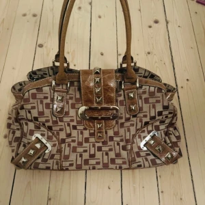Vinntage GUESS väska🔥 - Suuuper fin vintage Guess väska i jättefint skick🔥 Köpt för 1000 🔥💕 Insidan är som ny men är dock lite slitningar på nitarna men de e verkligen inget som syns i verkligheten 👏💕 🔥  Skriv om mått och bilder🔥🔥🔥