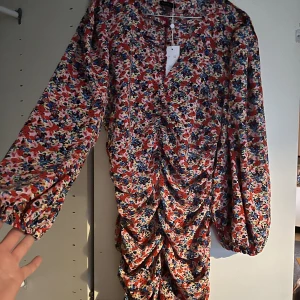 Draperad klänning - Draperad supersnygg klänning. Blommigt mönster. Ballongärm. Märke: Rut & Circle. Storlek L. 