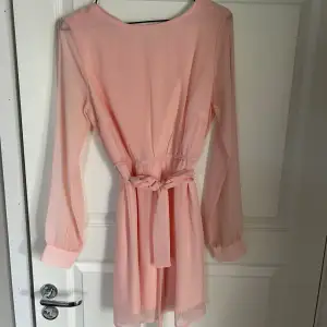 Rosa klänning som är perfekt nu till sommarn! Den har ett band i midjan som man knyta antingen i fram elelr bak! Lite genomskinligt material vid ärmarna!