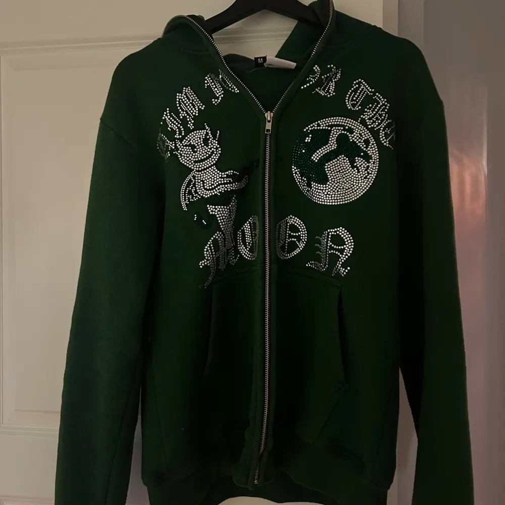 Säljer denna mörkgröna hoodie från ”Aim for the moon”.  Den är sparsamt andvänd i cirka 1 år. Saknas dock typ 3 pärlor på olika ställen, men inget som man märker av när man bär den.   storlek M    Hör av er om fler bilder osv! . Hoodies.