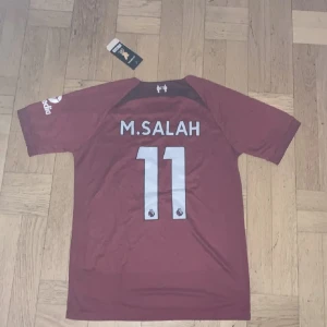 Liverpool tröja Salah  - En helt ny Liverpool tröja med nummer 11 på ryggen salah. Tags sitter kvar på tröjan då den är oanvänd.