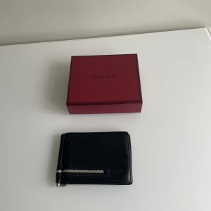 Bally plånbok - Då var det dags för den stilrena bally plånbok att säljas, en enkel plånbok med skick 6-7/10  Köpt för 2800 för några år sedan i butik men har tyvär tappat bort kvittot under åren där av sänks priset! Priset kan diskuteras Vid frågor hör av er!