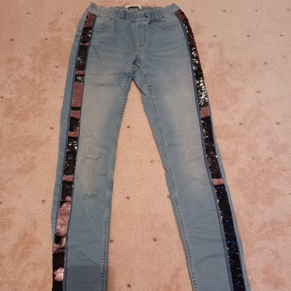 Säljer nu dessa coola och unika jeans som är blå med paljetter på sidorna som är svarta och rosa. De är sparsamt använda och därför i bra skick. Storleken är 164 men passar också xs . Jeans & Byxor.