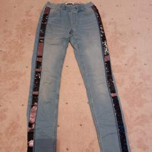 Säljer nu dessa coola och unika jeans som är blå med paljetter på sidorna som är svarta och rosa. De är sparsamt använda och därför i bra skick. Storleken är 164 men passar också xs 