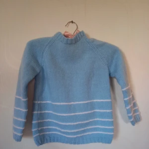 Stickad tröja  - Blå stickad tröja i super bra skick, nästan aldrig använd. Har vita ränder på den nedre delen av tröjan. Det står ingen storlek men skulle säga att den passar ungefär 6 åringar.