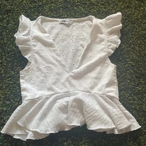 Tjusande vit blus med volang - Jätte fin blus, passar att kombinera med alla sorters plagg. Får en glad och positiv känsla när jag ser den. Rekommenderar för er som är förtjusta i Stockholmsstilen. Storleken är S och passar mycket bra på mig som är 167 cm
